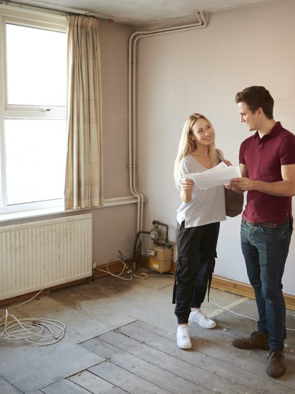 couple-buying-house-for-first-time-looking-at-house-survey-in-room-to-be-renovated.jpg